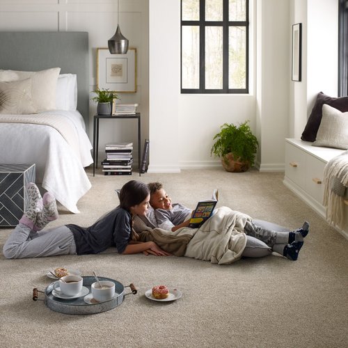 two kids laying on carpet reading a book