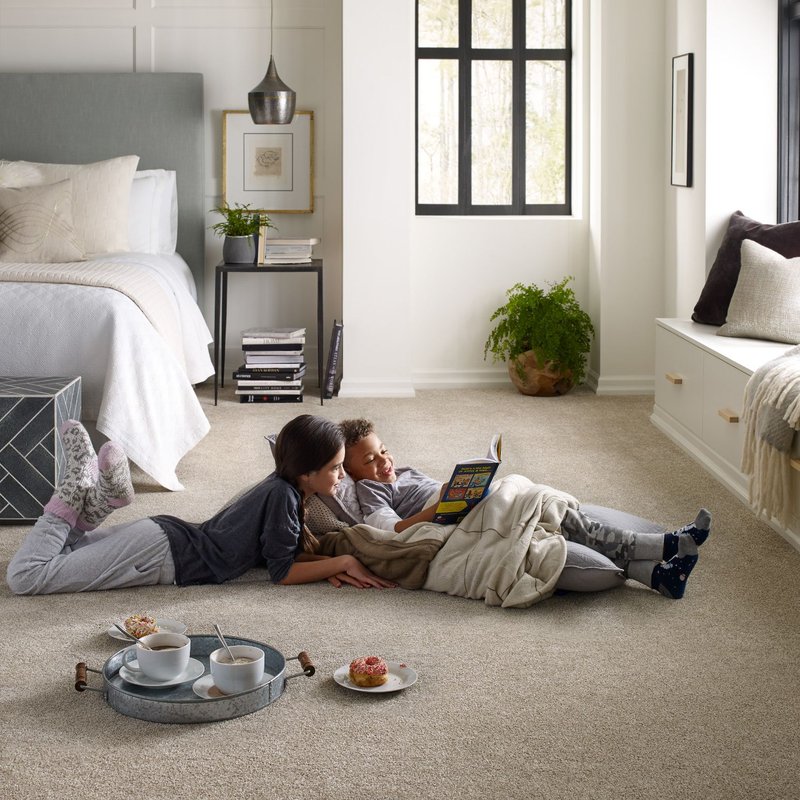 two kids laying on carpet reading a book